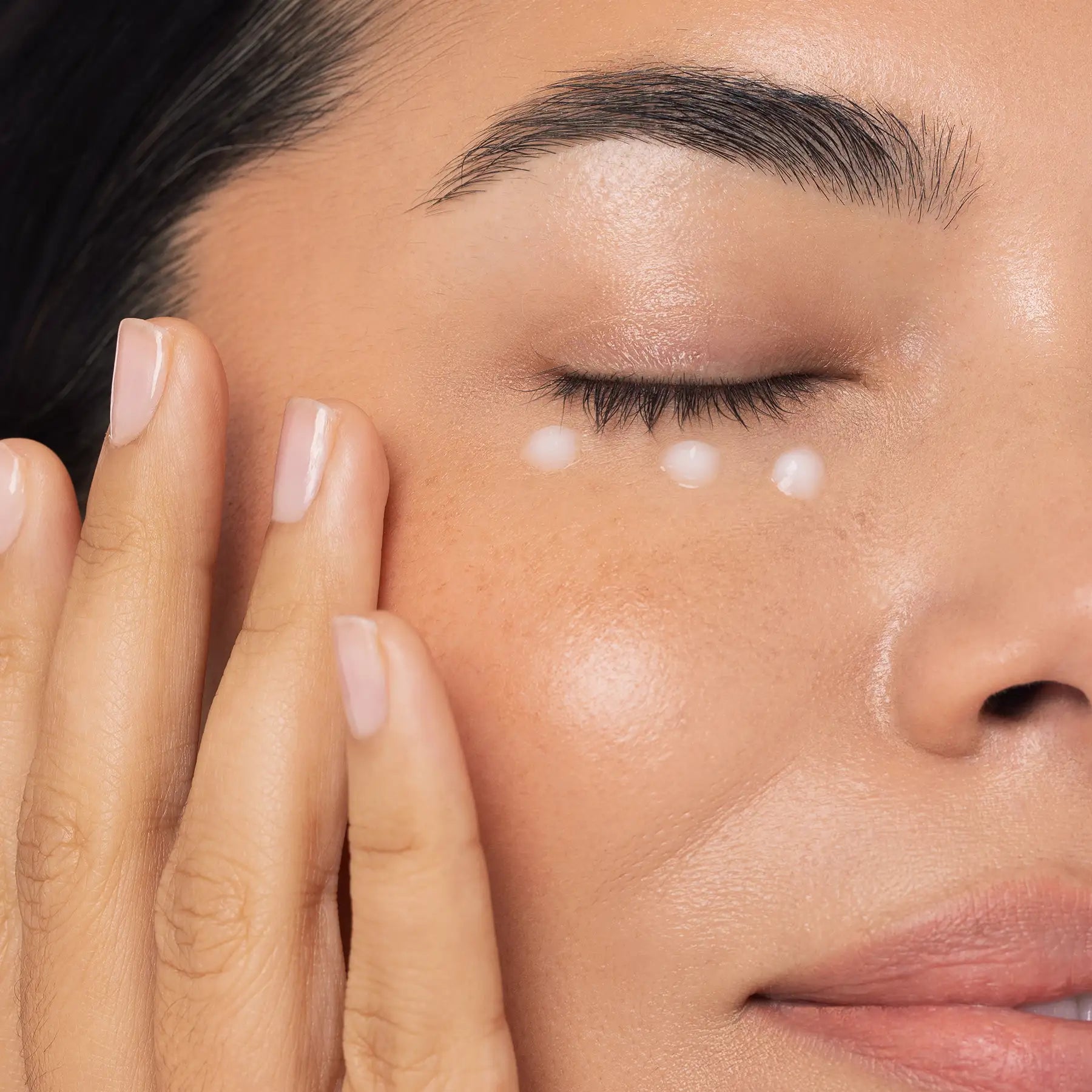 Close-up of a person applying a skincare product to their face