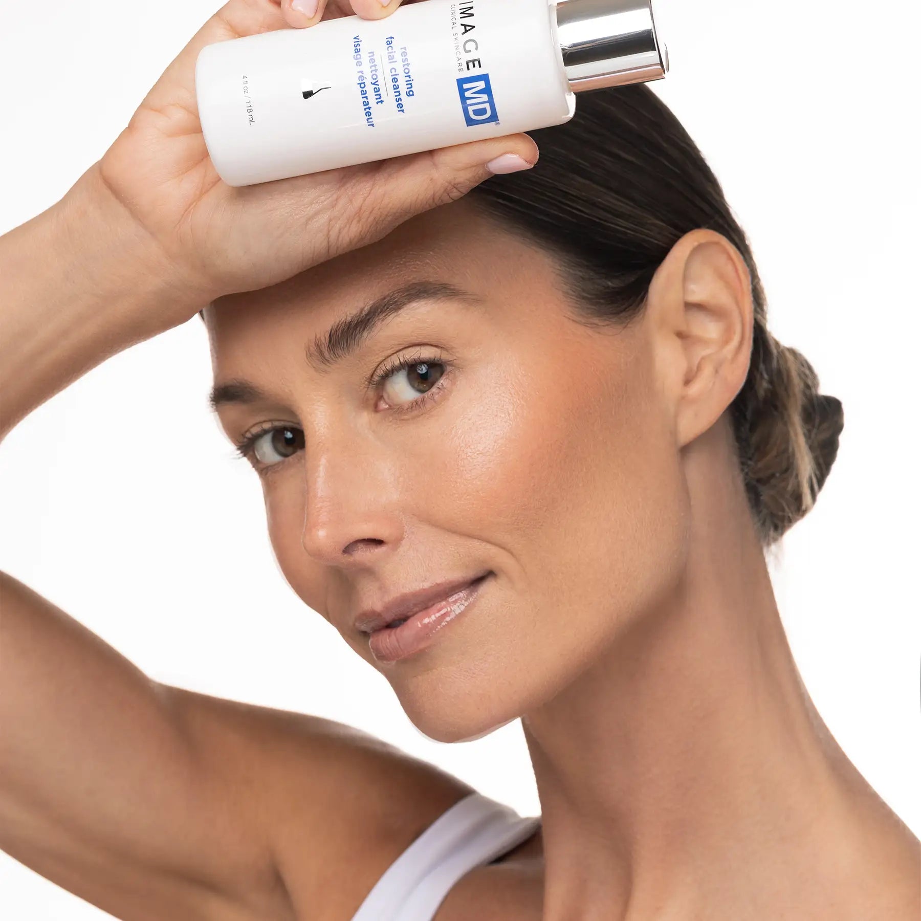 Woman applying skincare product to her face with a white background