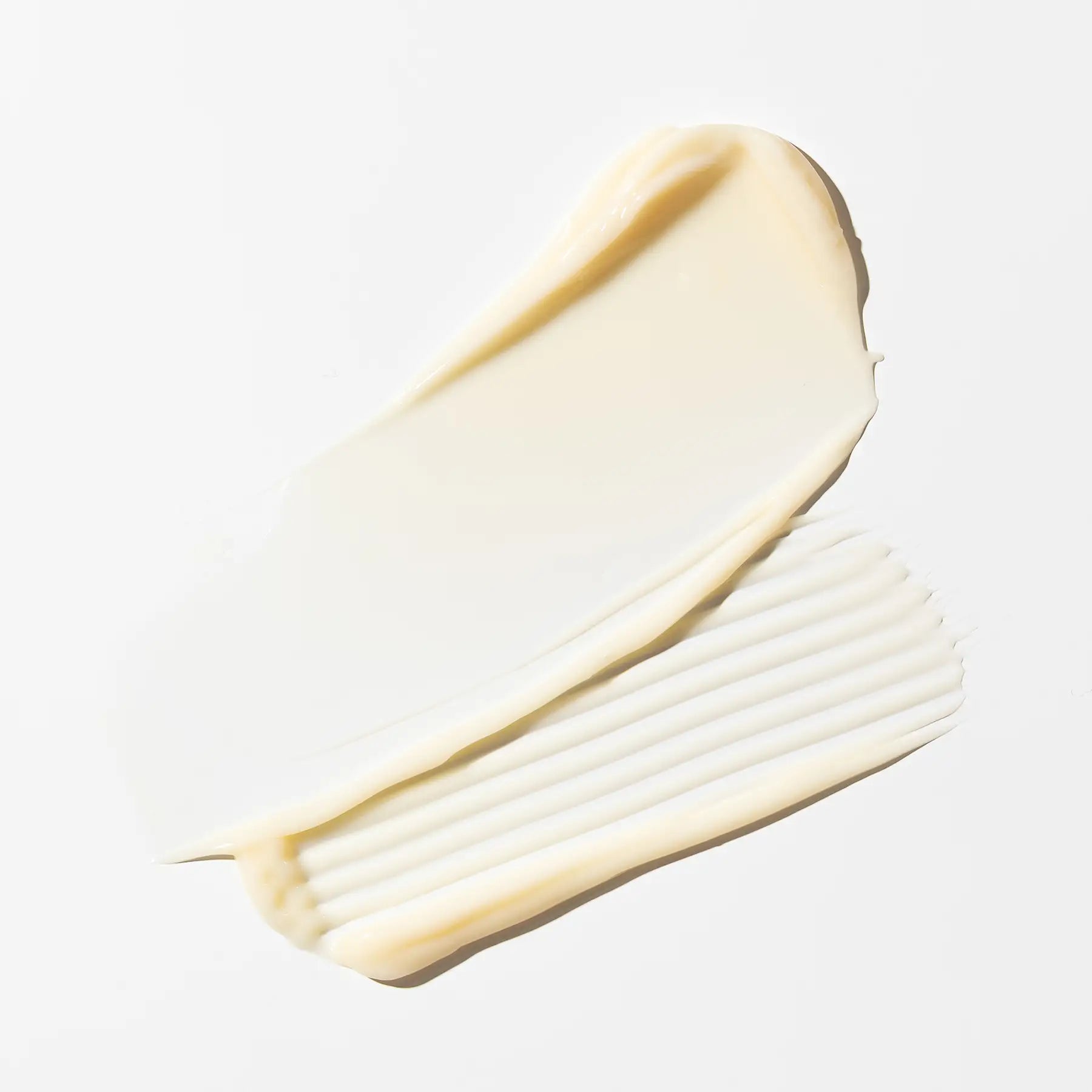 Two swatches of white cream on a light gray background