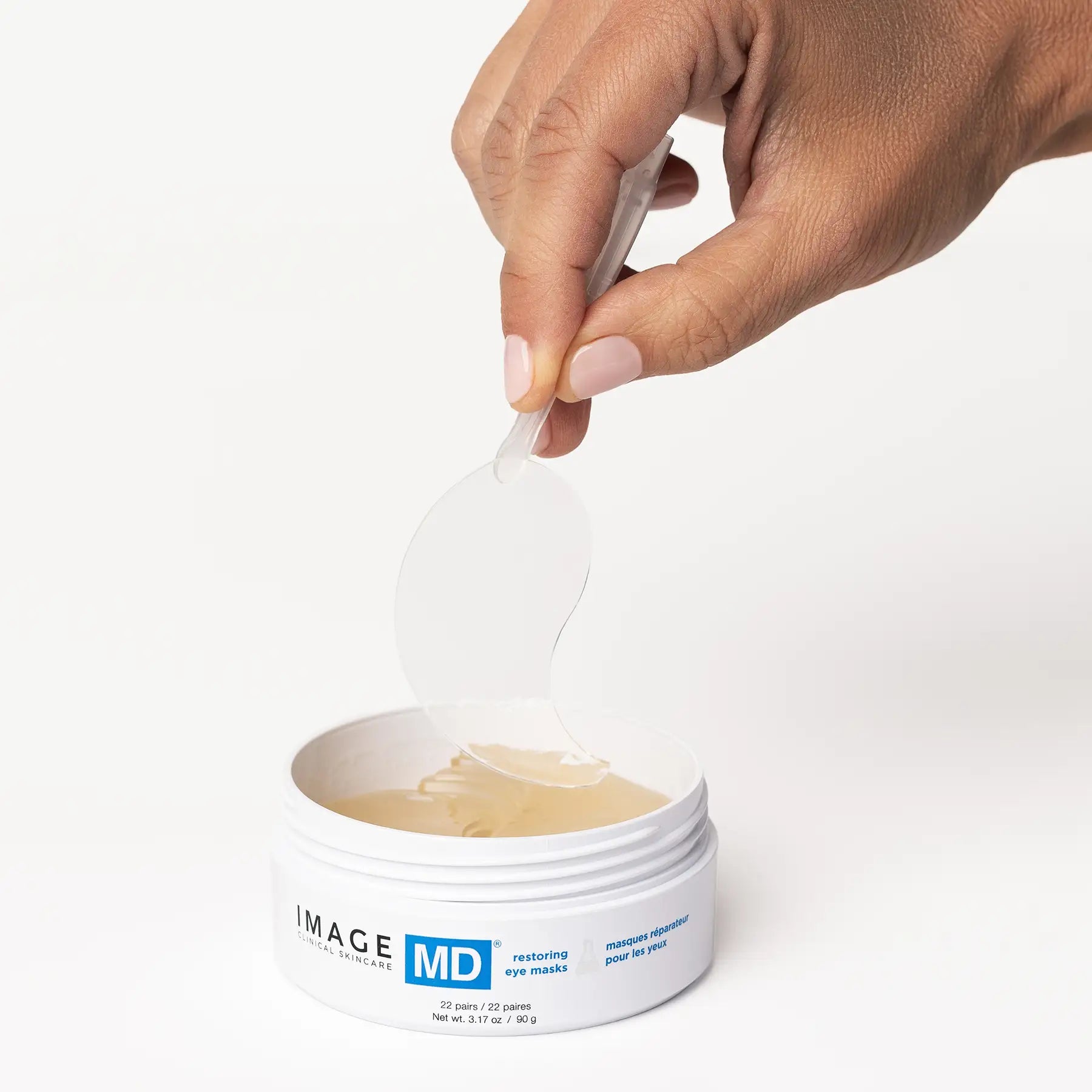 Hand picking up eye masks from an 'IMAGE MD' container on a white background