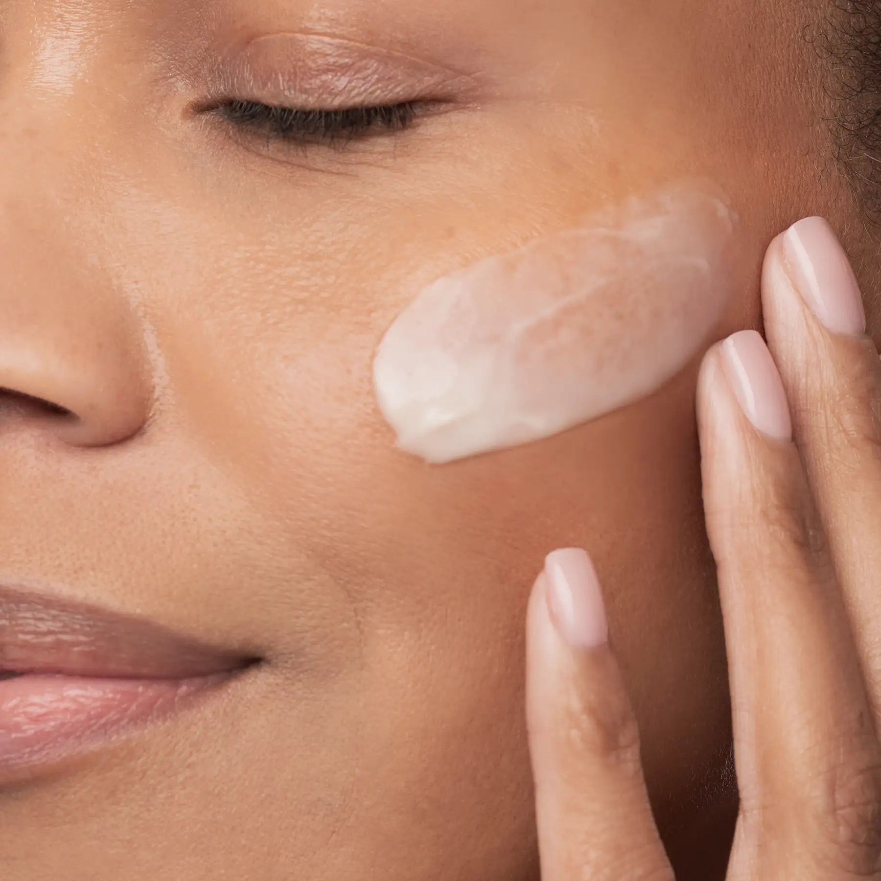 Close-up of a woman applying cream to her face
