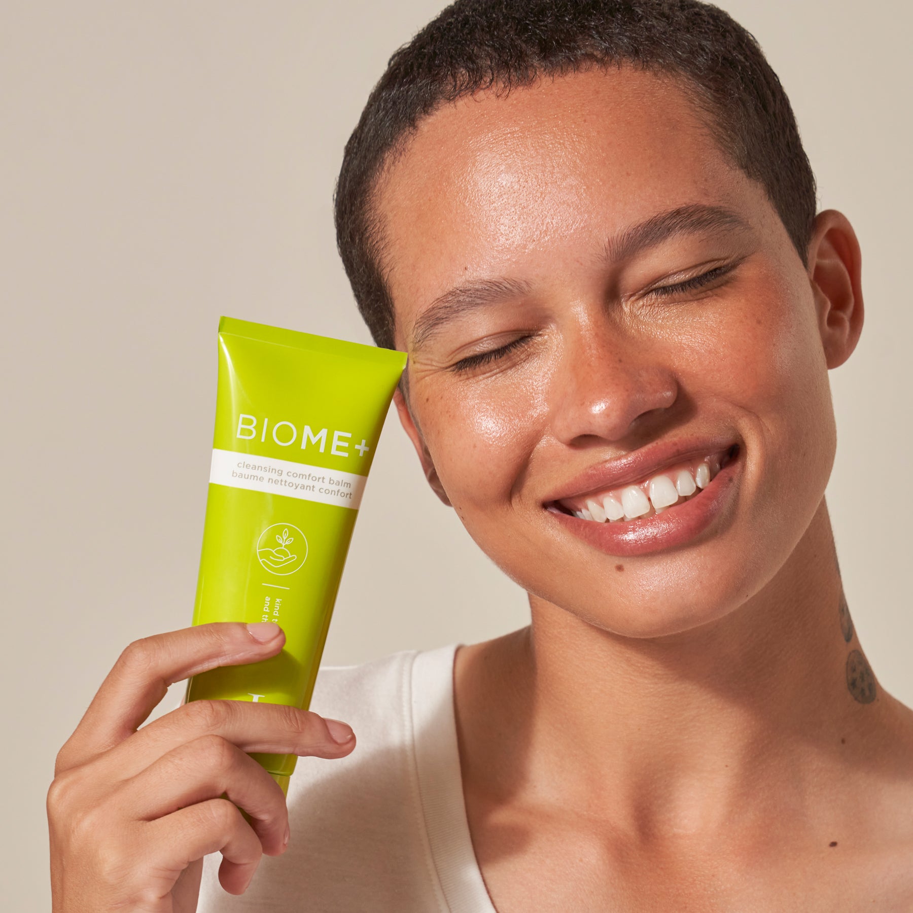 model holding cleansing comfort balm tube up to face