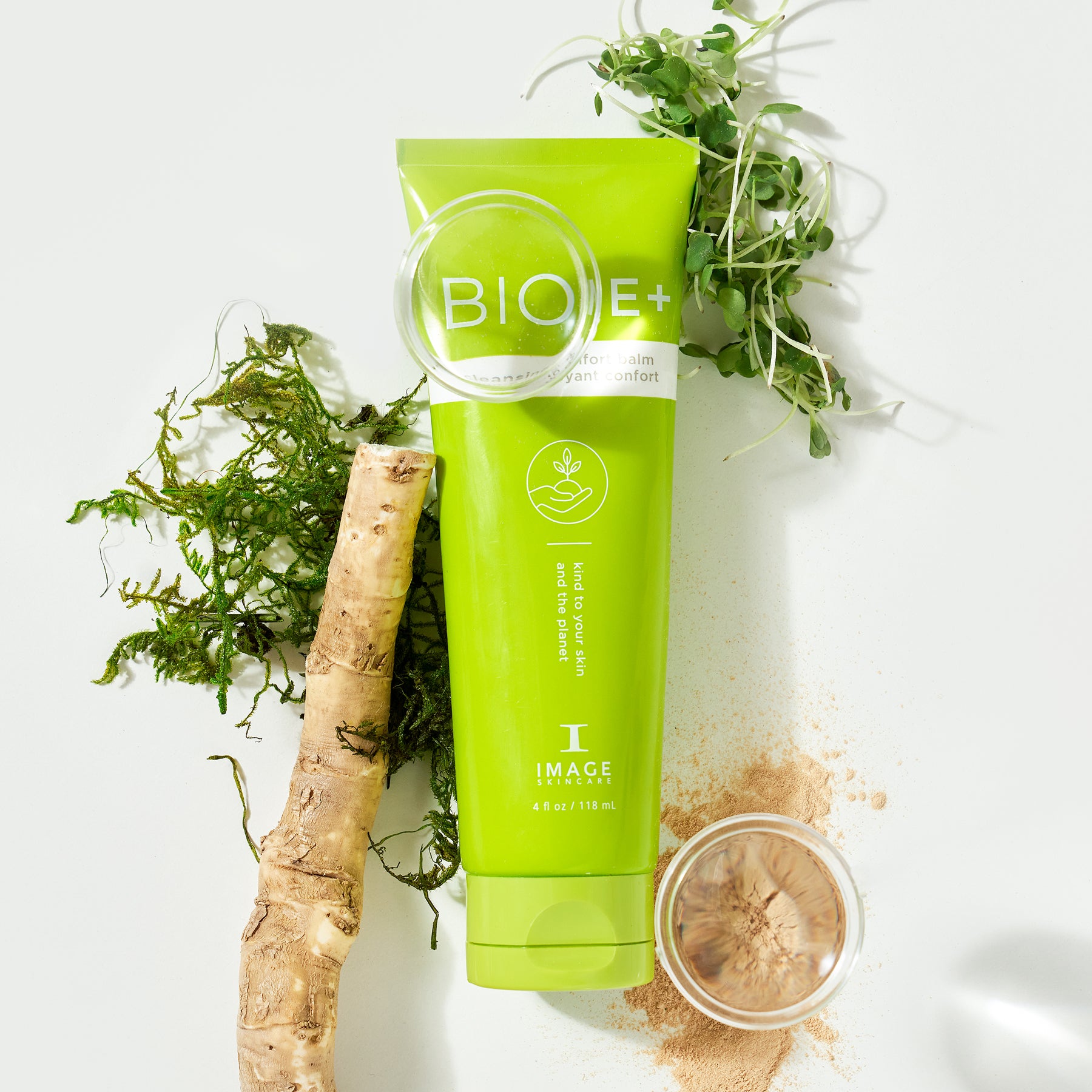 Biome+ cleansing comfort balm tube laid in between petri dishes with ingredients and plant leaves