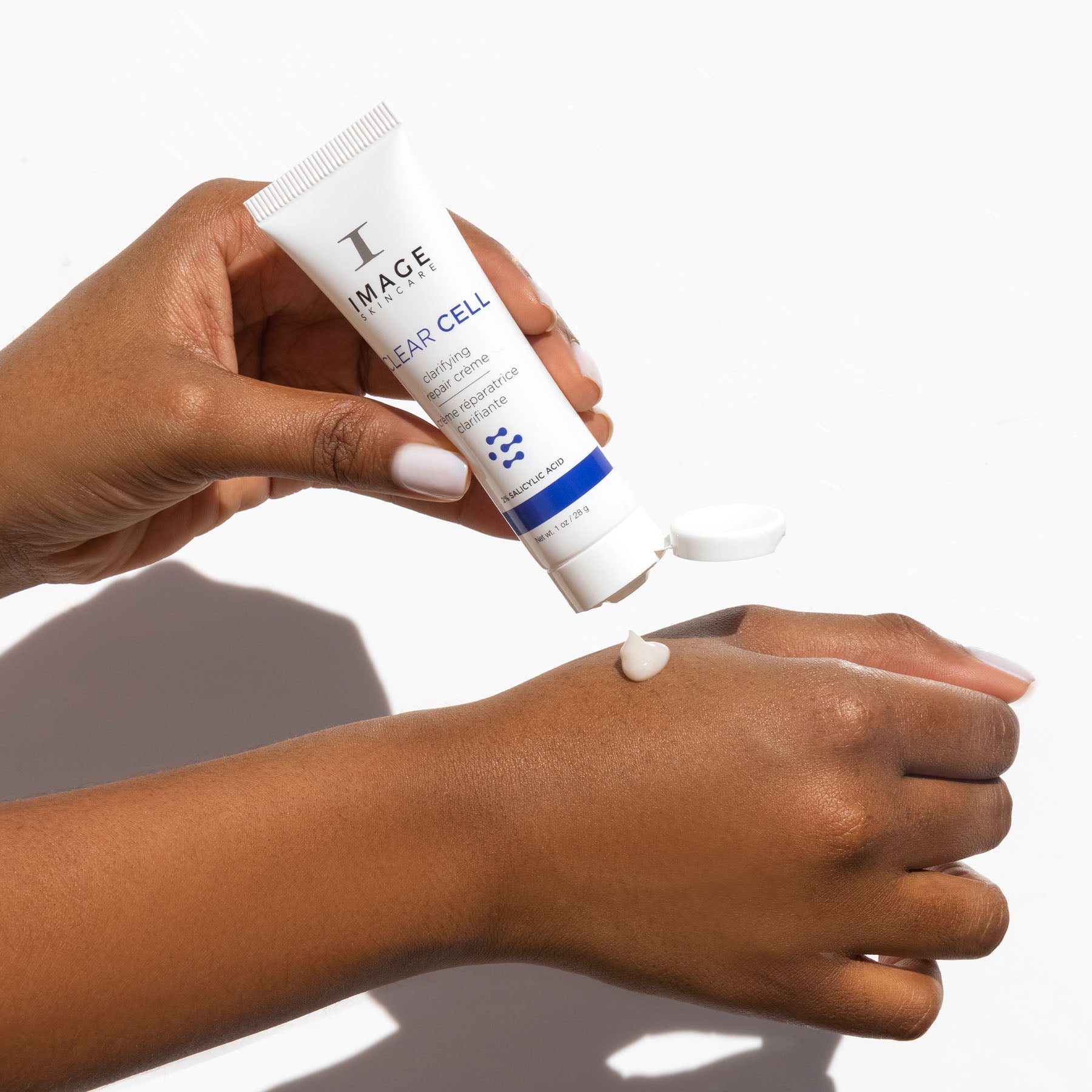 model hands holding Discovery-size CLEAR CELL clarifying repair crème and dispensing creme onto hand