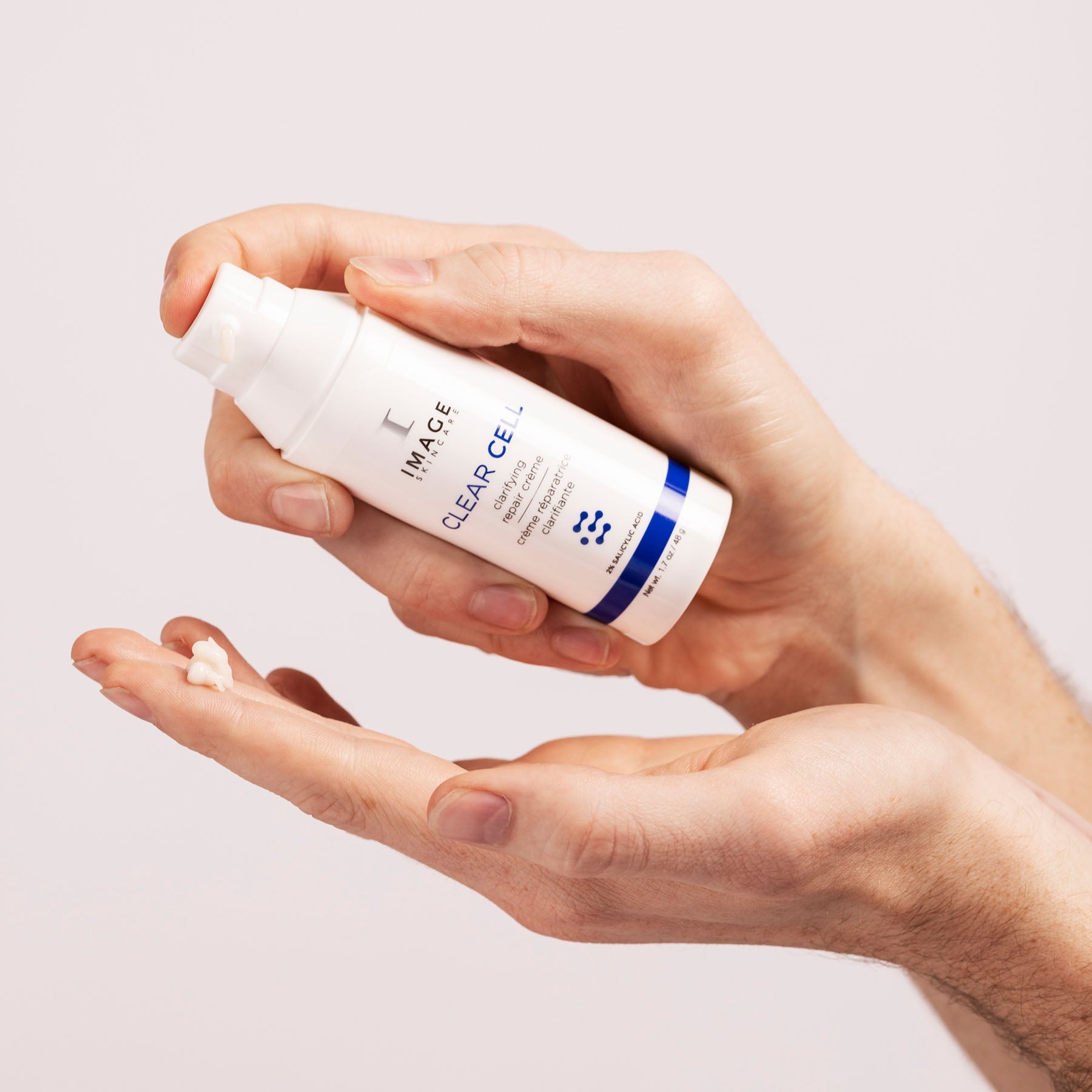model hands holding CLEAR CELL clarifying repair crème and dispensing product onto finger