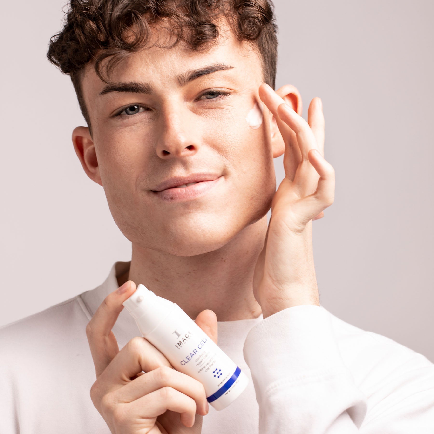 model applying CLEAR CELL clarifying repair crème to cheek