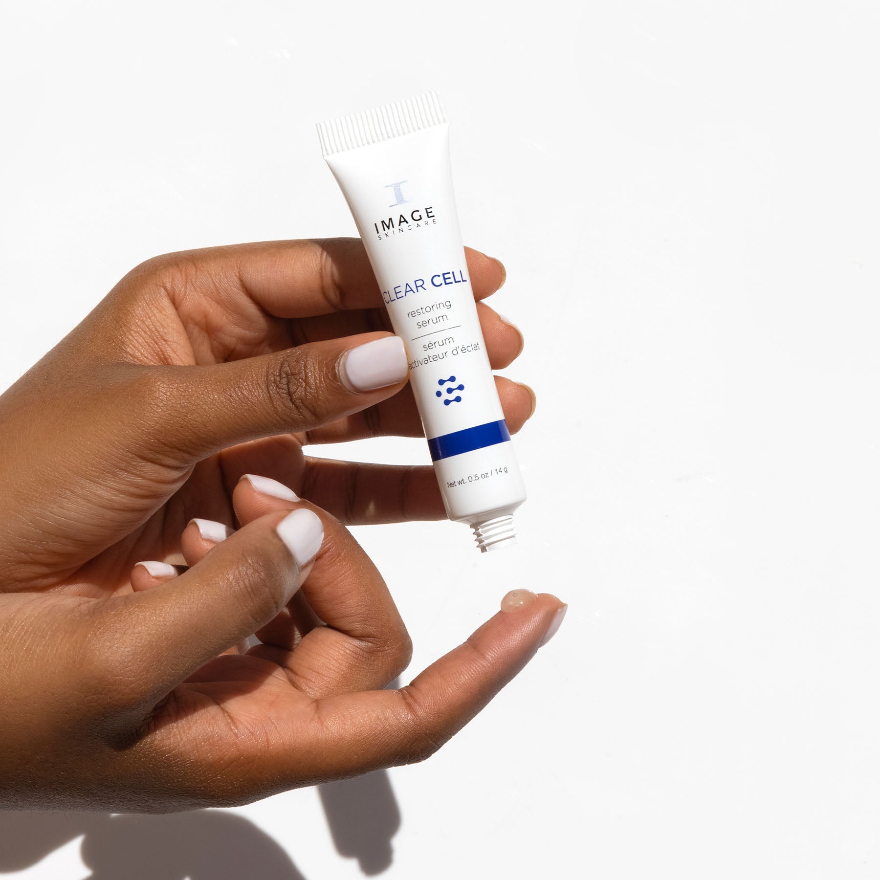 model holding travel size restoring serum and dispensing drop on finger