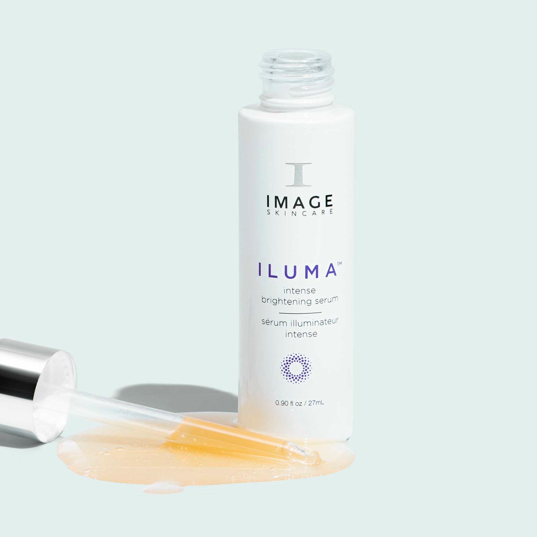 iluma brightening serum open bottle with dropper spilling liquid on light background