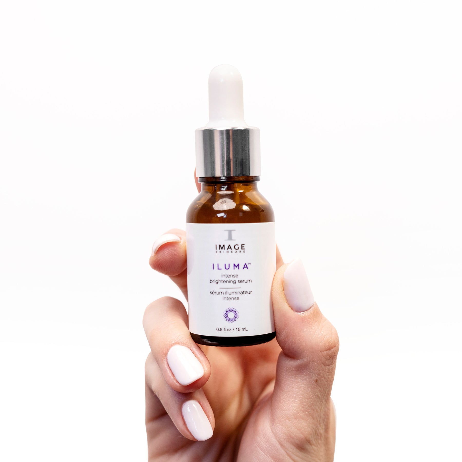model hand holding bottle of travel size iluma brightening serum