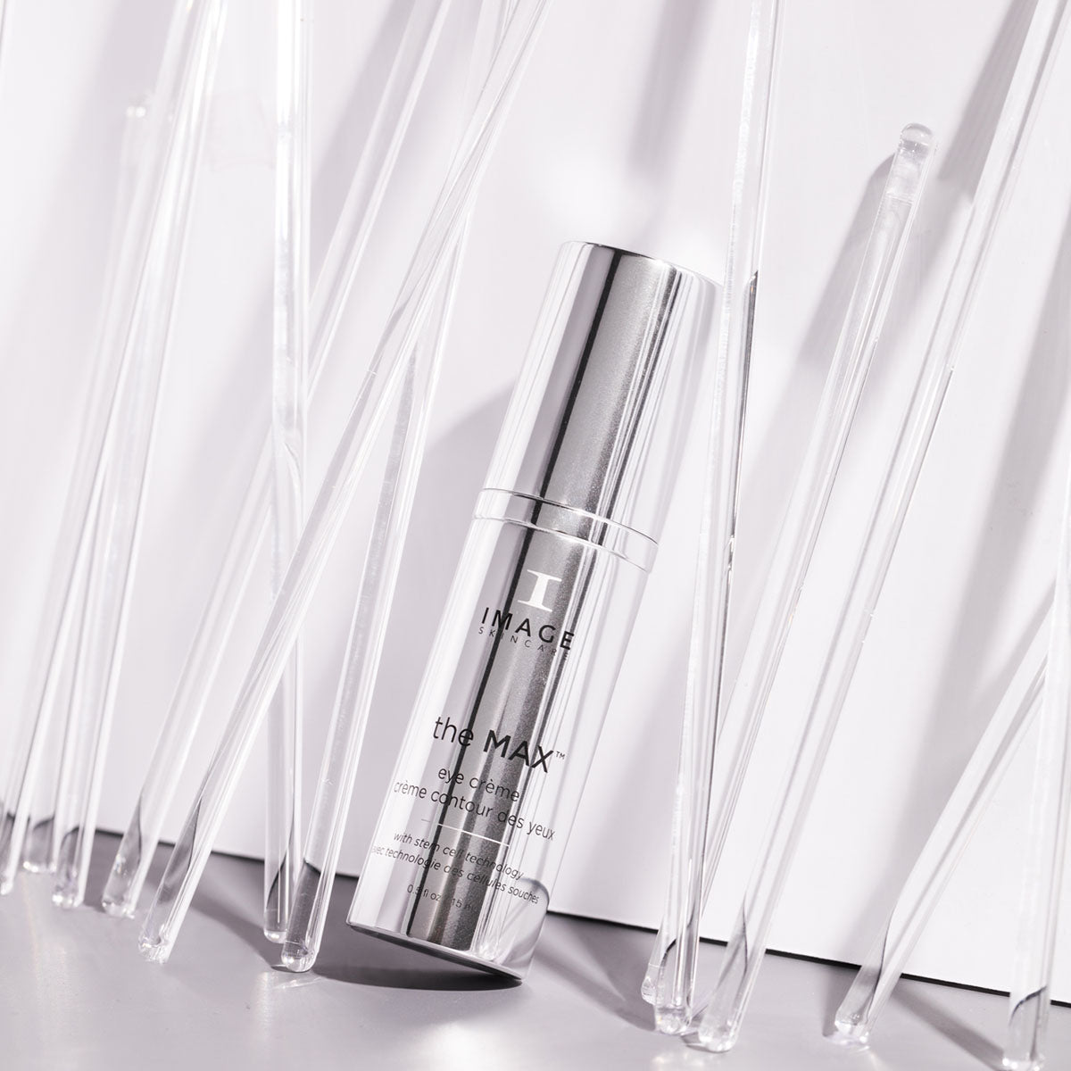 max eye creme bottle leaning against white wall surrounded by stirrers