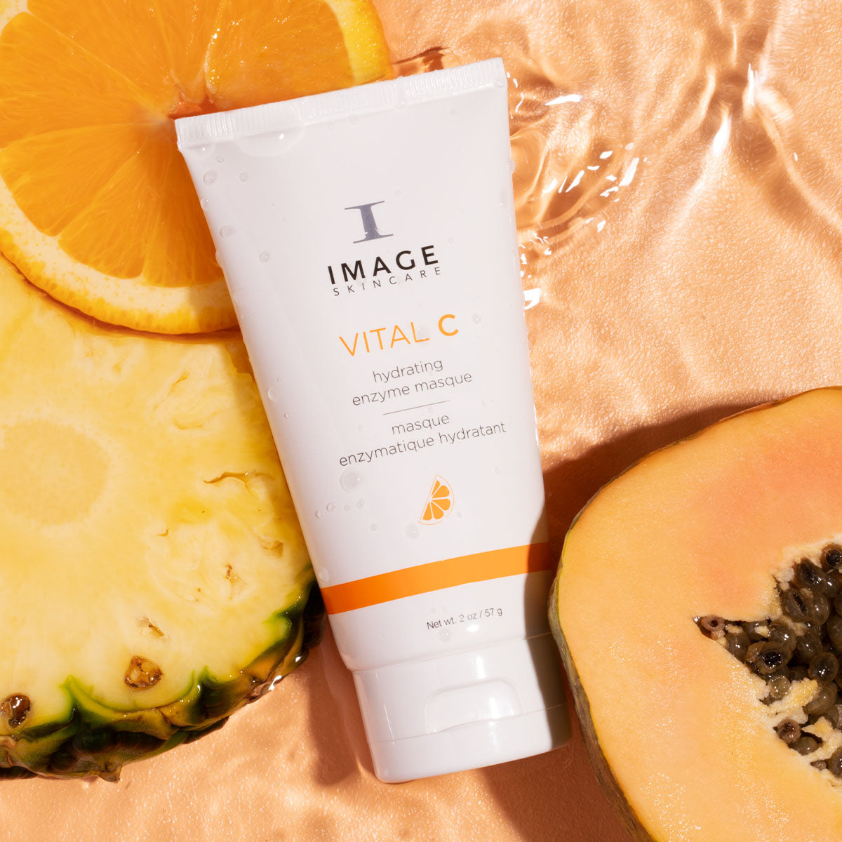 enzyme masque product on an orange background next to pineapple, orange slice, and sliced papaya