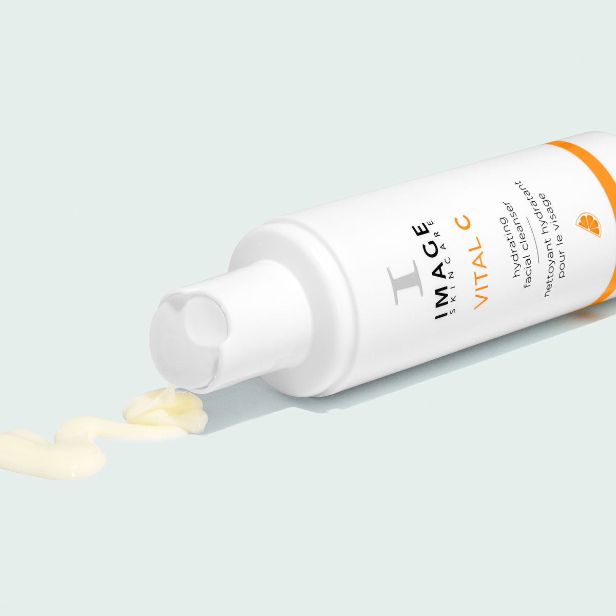 bottle of cleanser open with cleanser pouring out on light background