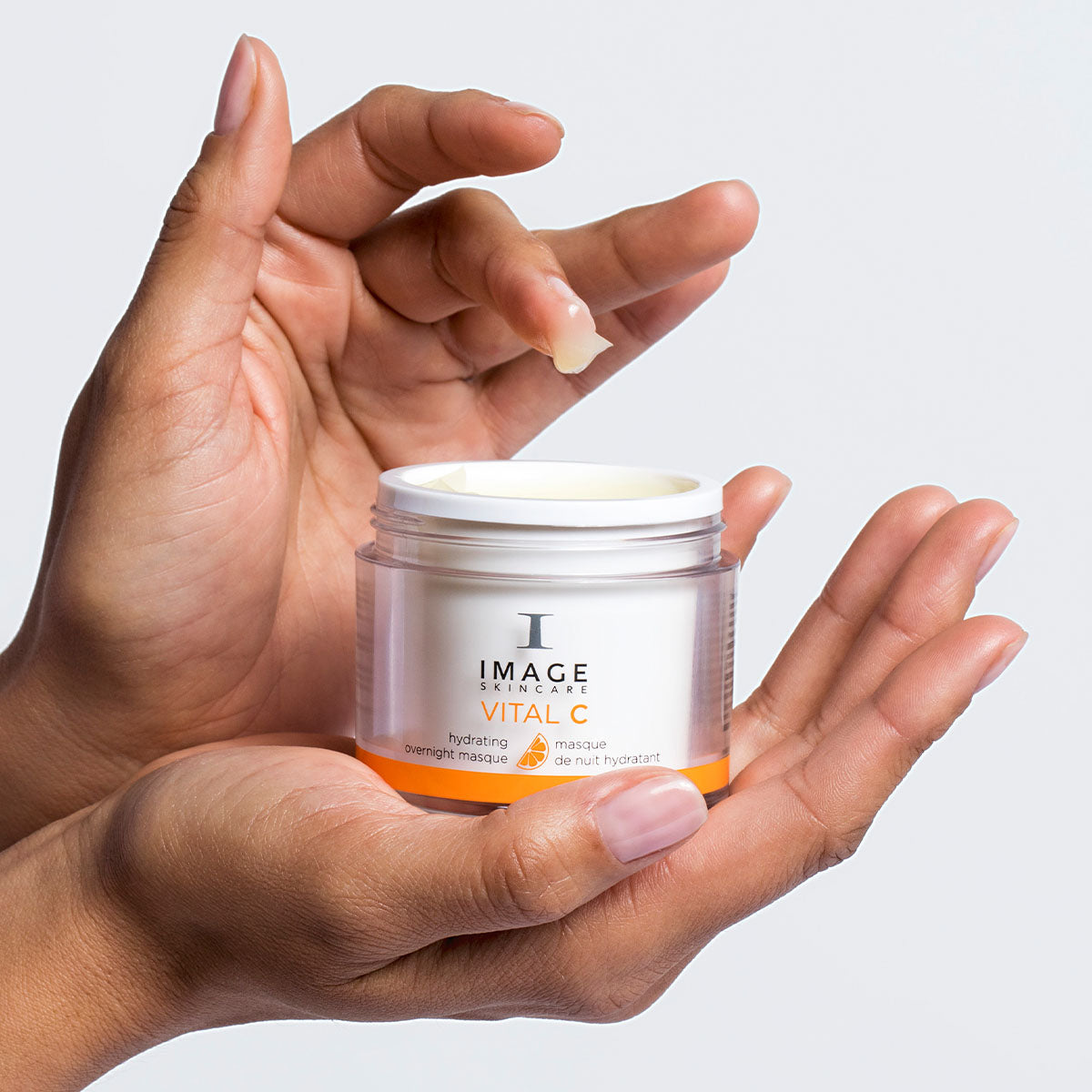 model hands holding overnight masque product with finger dipped in the masque