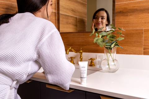 Woman applying AGELESS total microderm exfoliator in her bathroom
