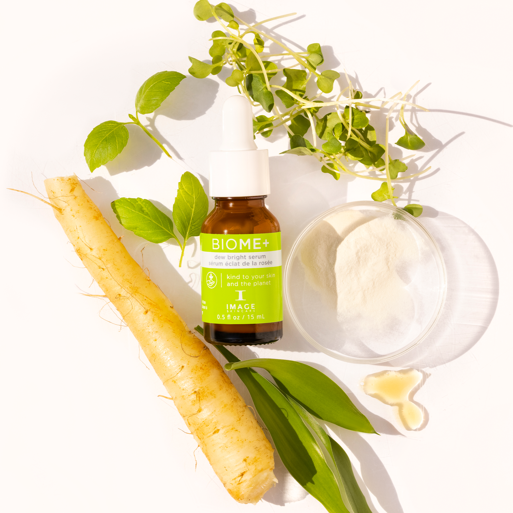 Biome+ dew bright serum travel size bottle laid in between petri dishes with ingredients and plant leaves