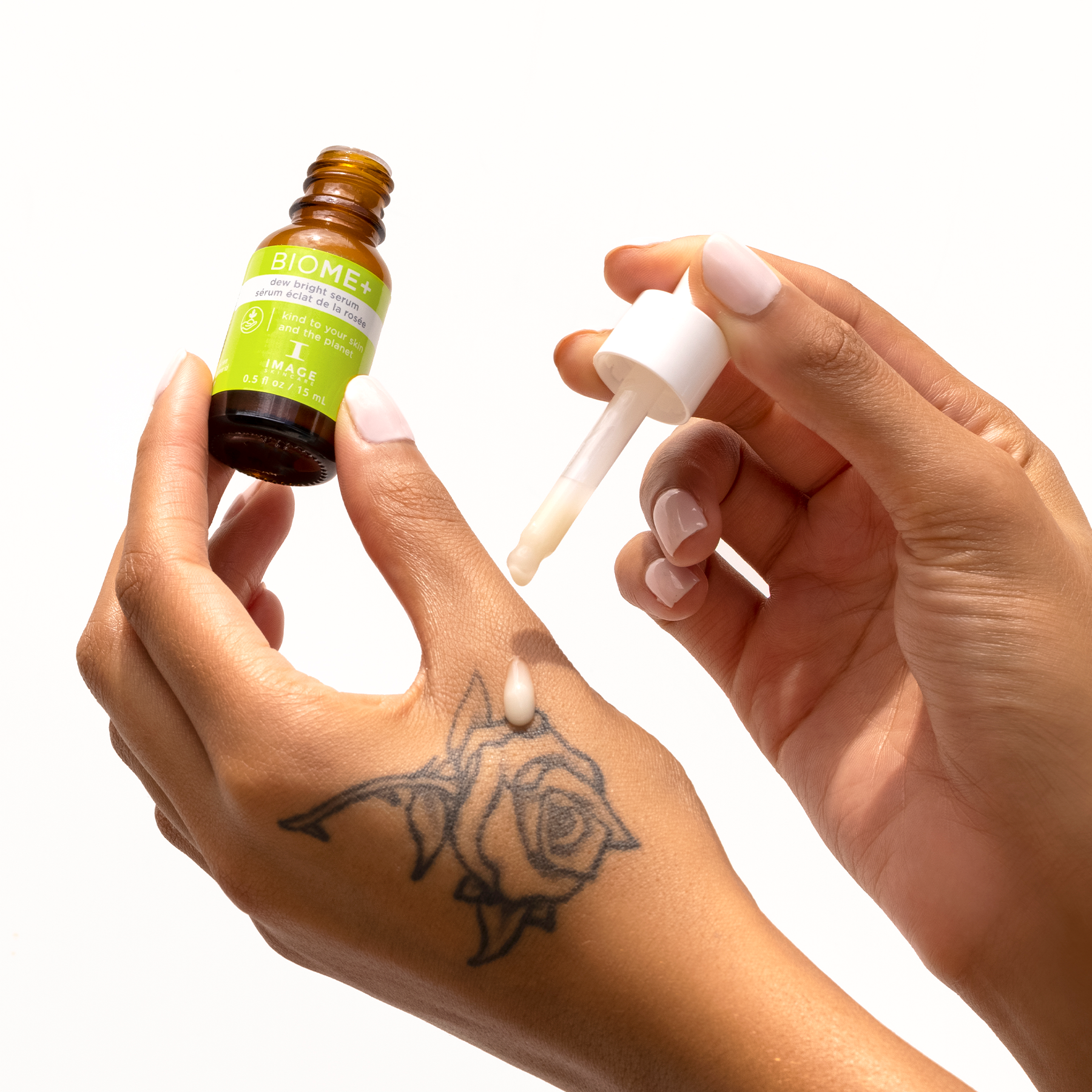 model holding travel size dew bright serum bottle applying product onto hand with dropper